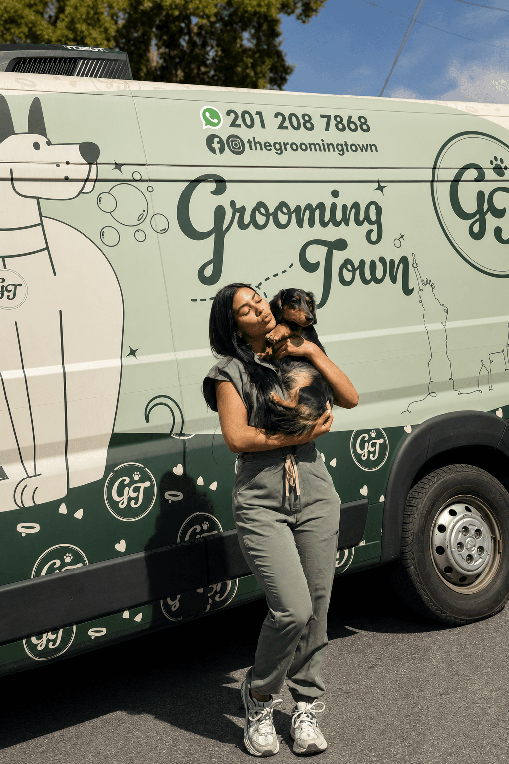 Solmary holding a dachshund close outside the Grooming Town van